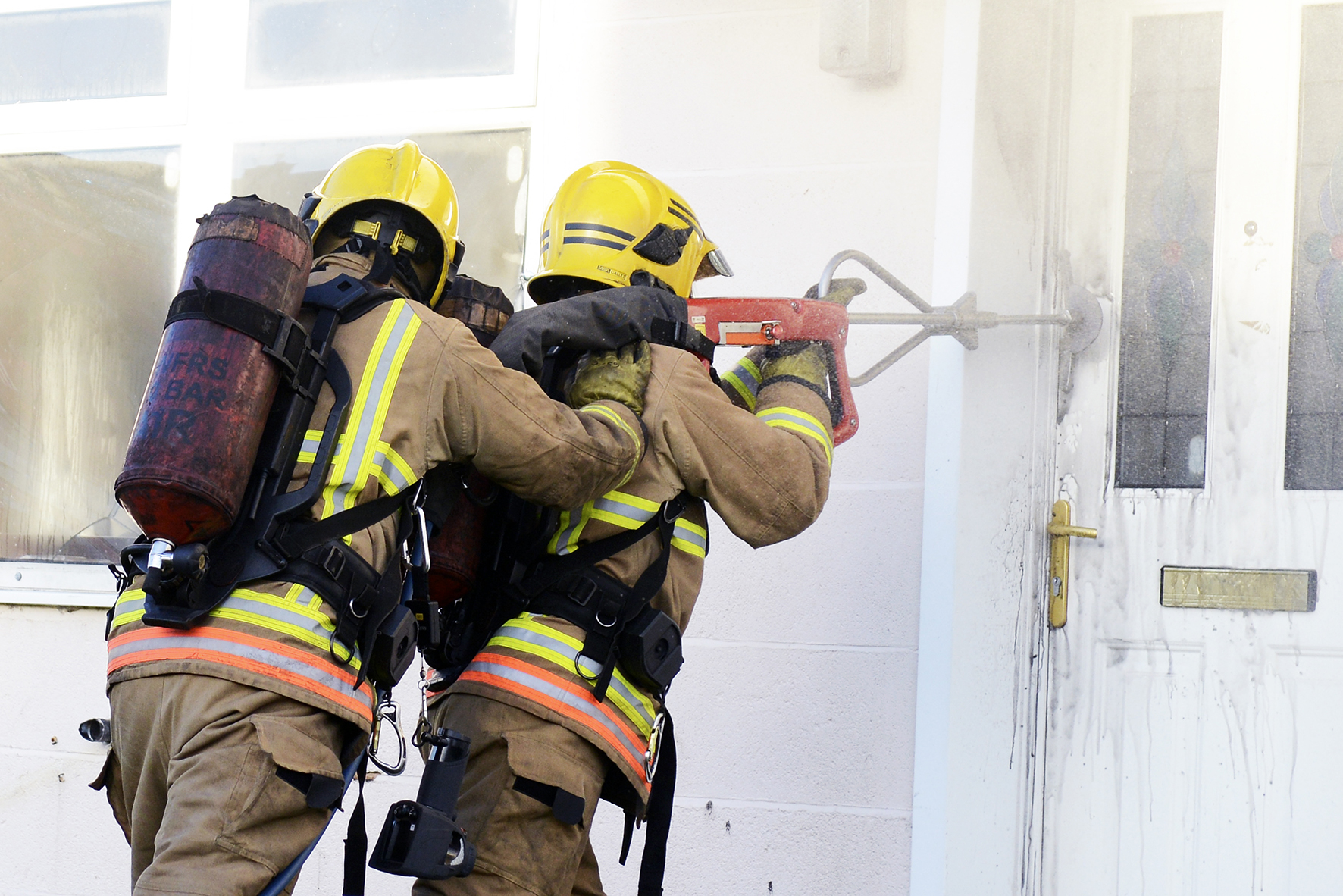 Photograph of two firefighters at the door of a house using the Cobra Extinguishing System
