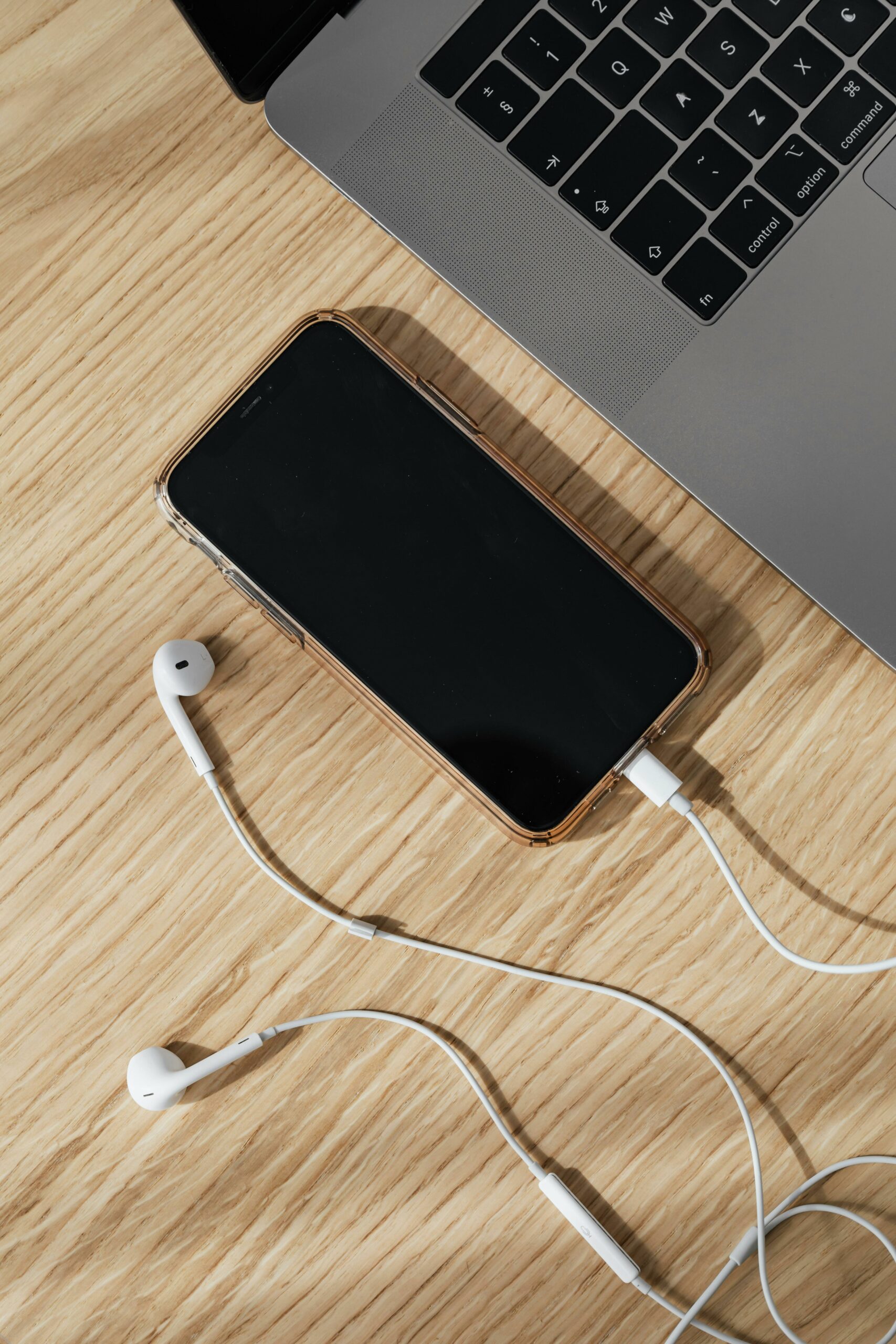 Photograph of a laptop and a mobile phone with headphones plugged into it