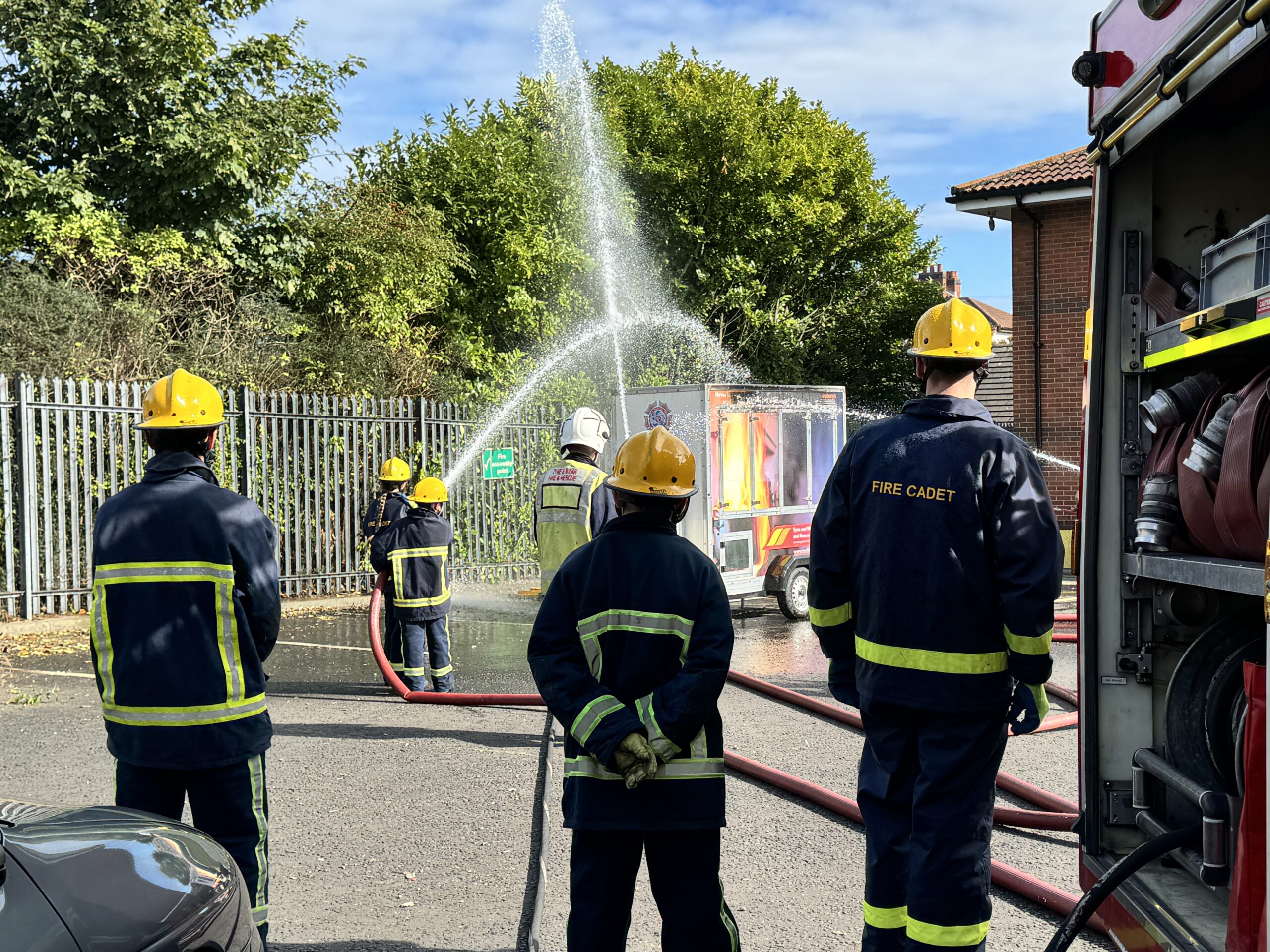 Photograph of fire Cadets training with fire engines, hoses and equipment