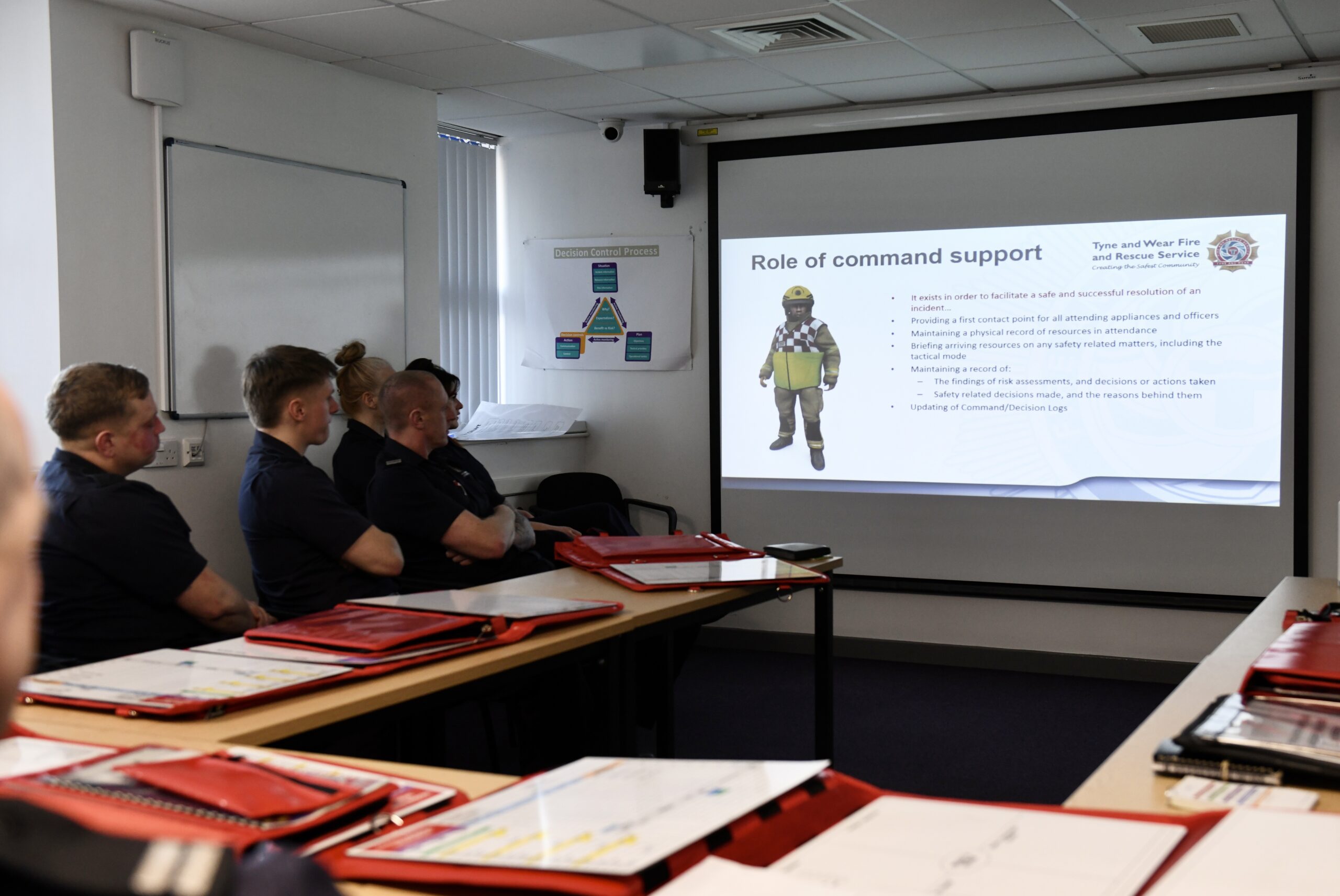 Firefighters sitting in a lecture room viewing a presentation slide of training