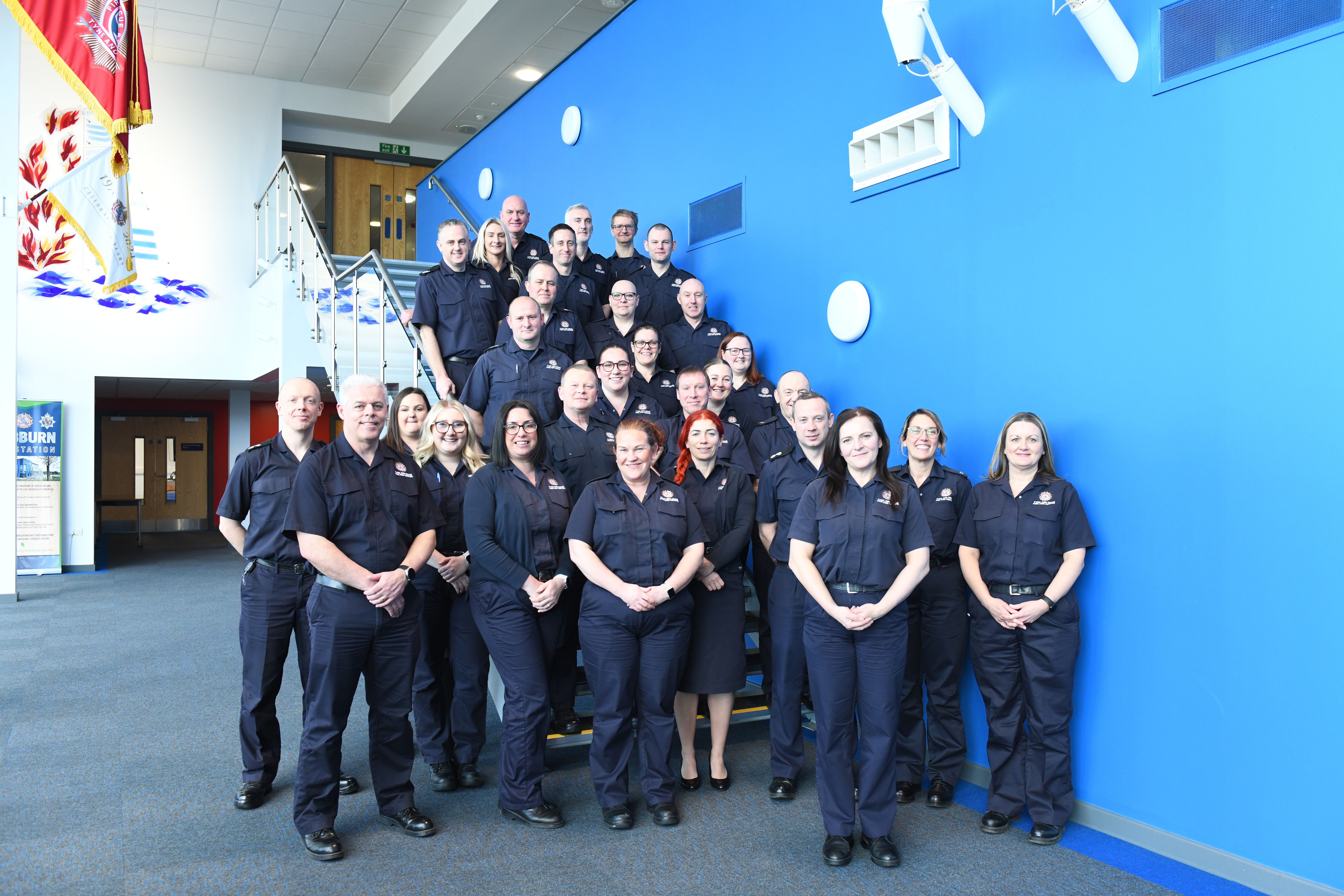 photograph of staff standing as a group on a set of stairs smiling