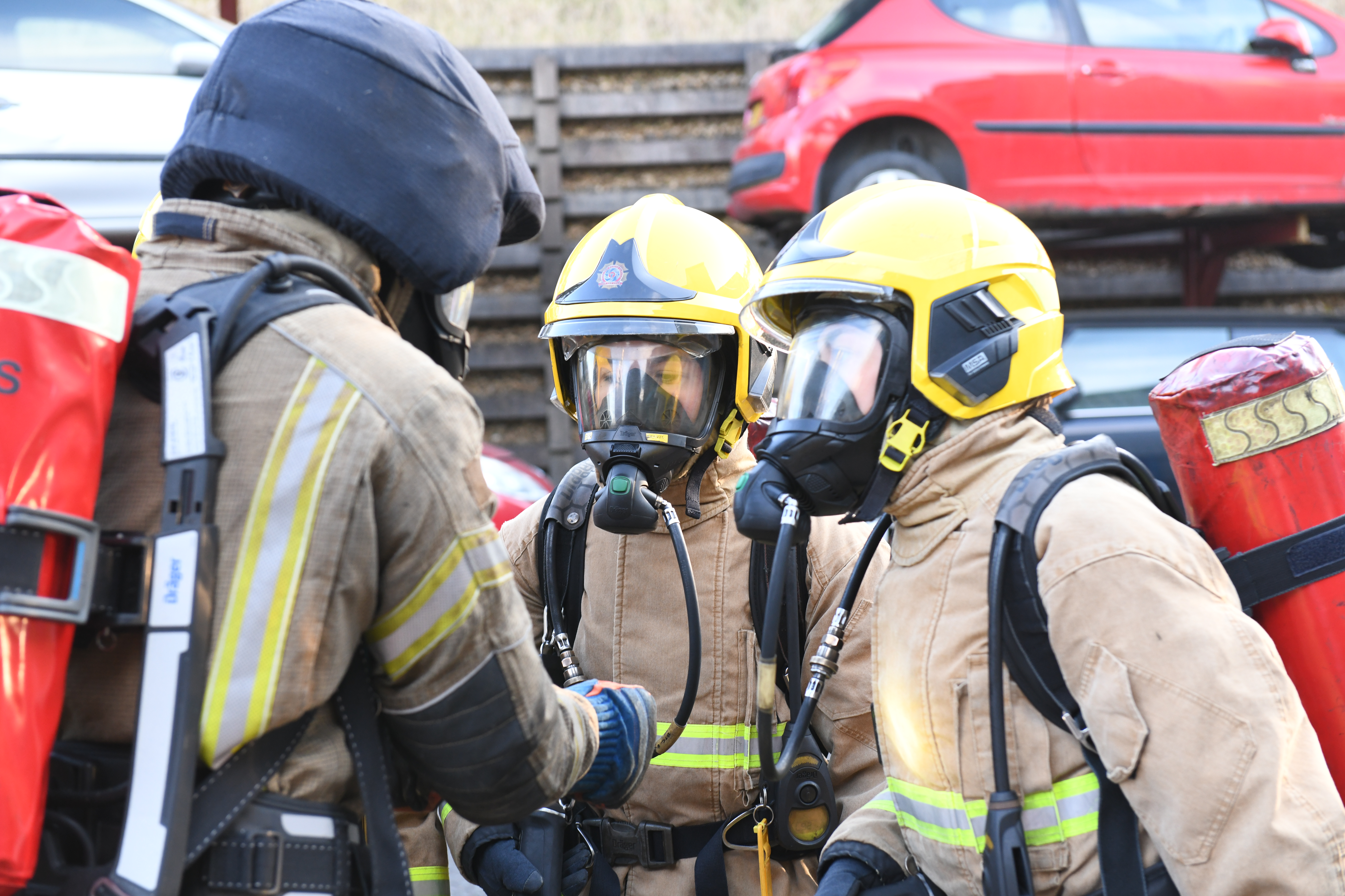 Three firefighters, wearing full gear including breathing apparatus