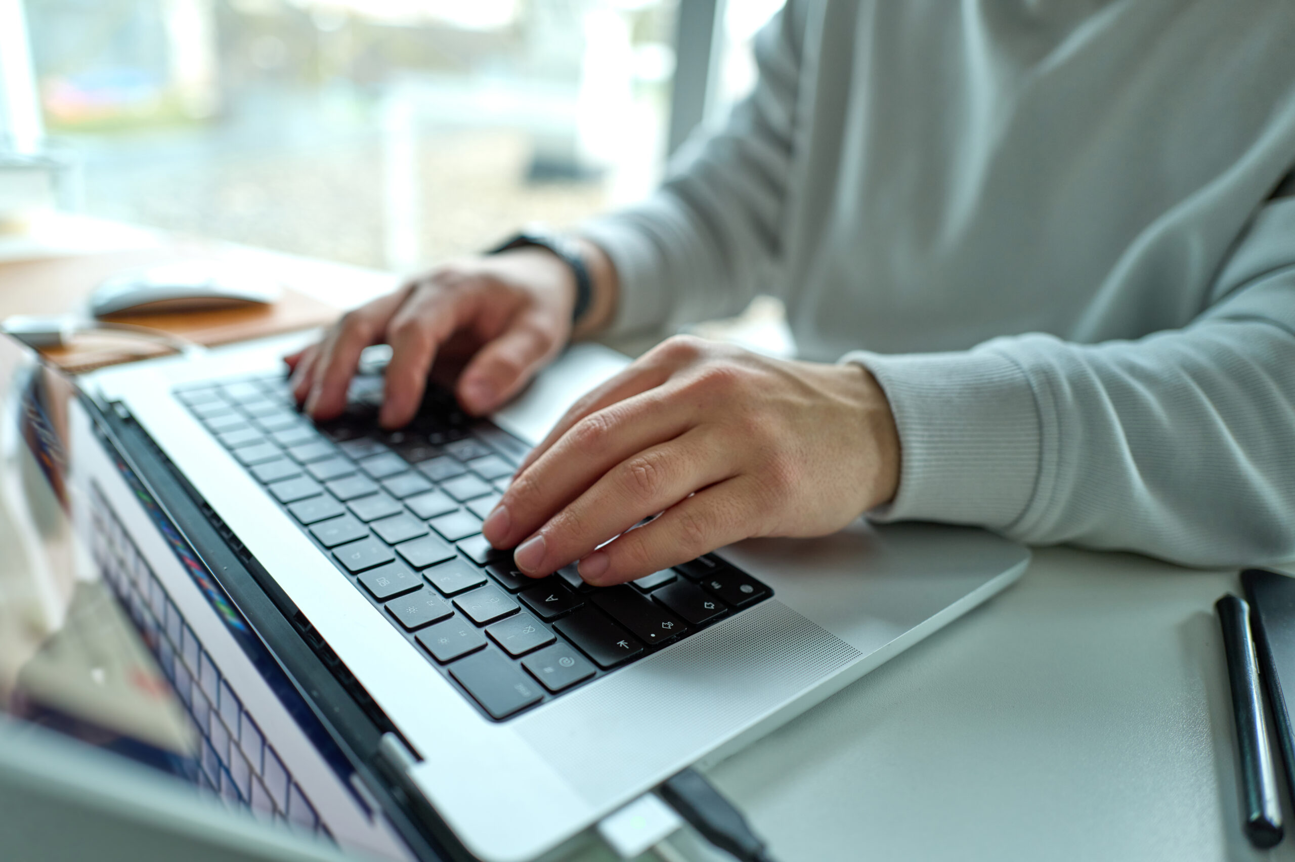 Data request - a person wearing a grey jumper typing the keys of a laptop.