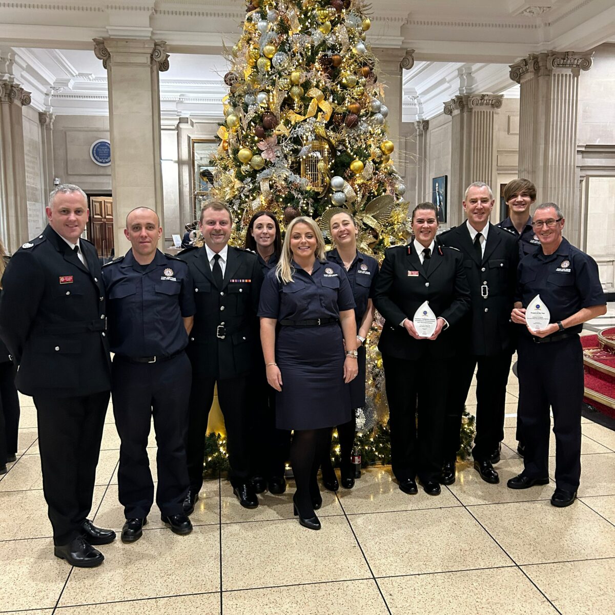 Photograph of staff from TWFRS at an awards ceremony, in front of a large Christmas tree