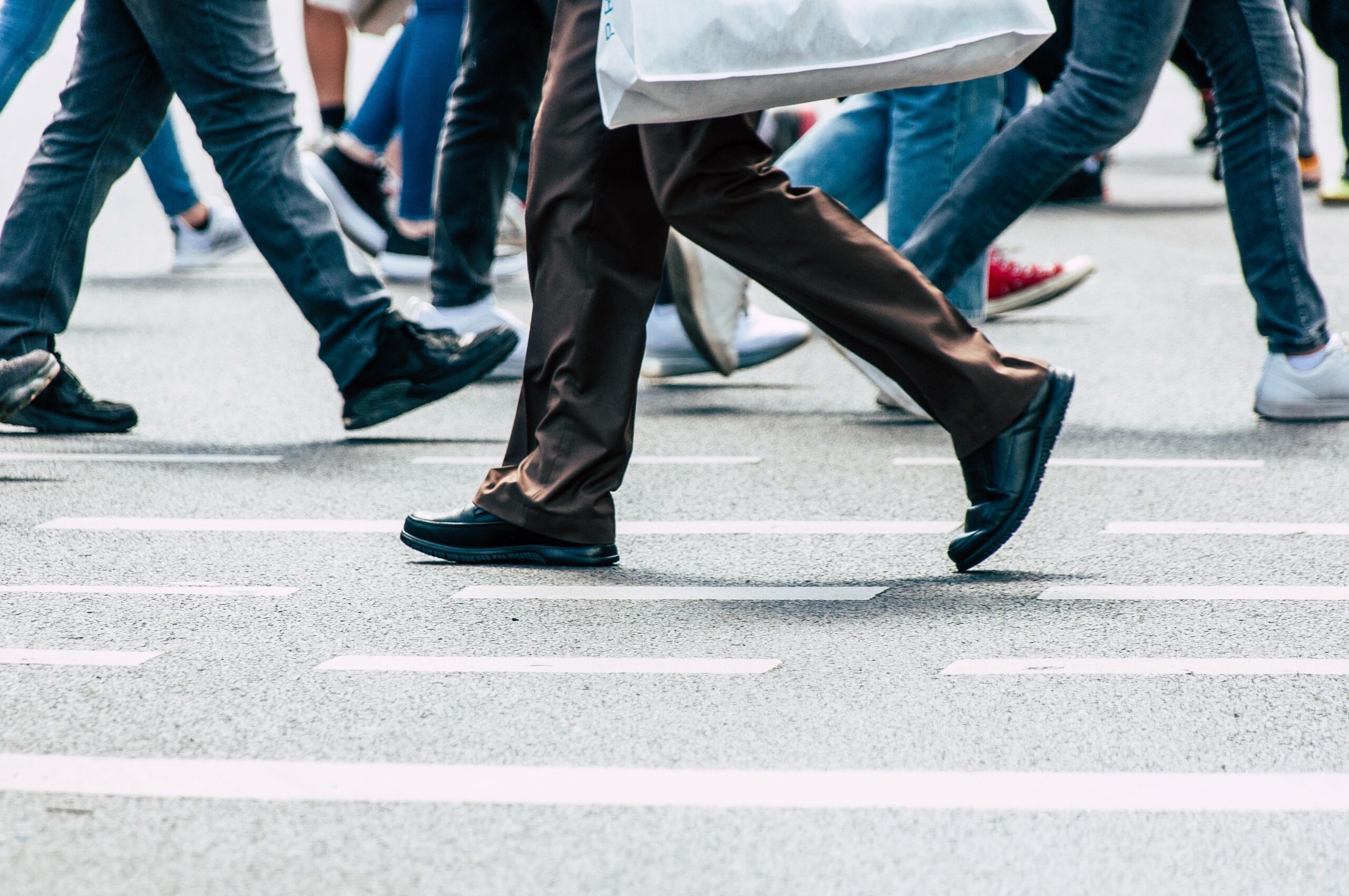People walking across a busy road with the main focus being their legs.