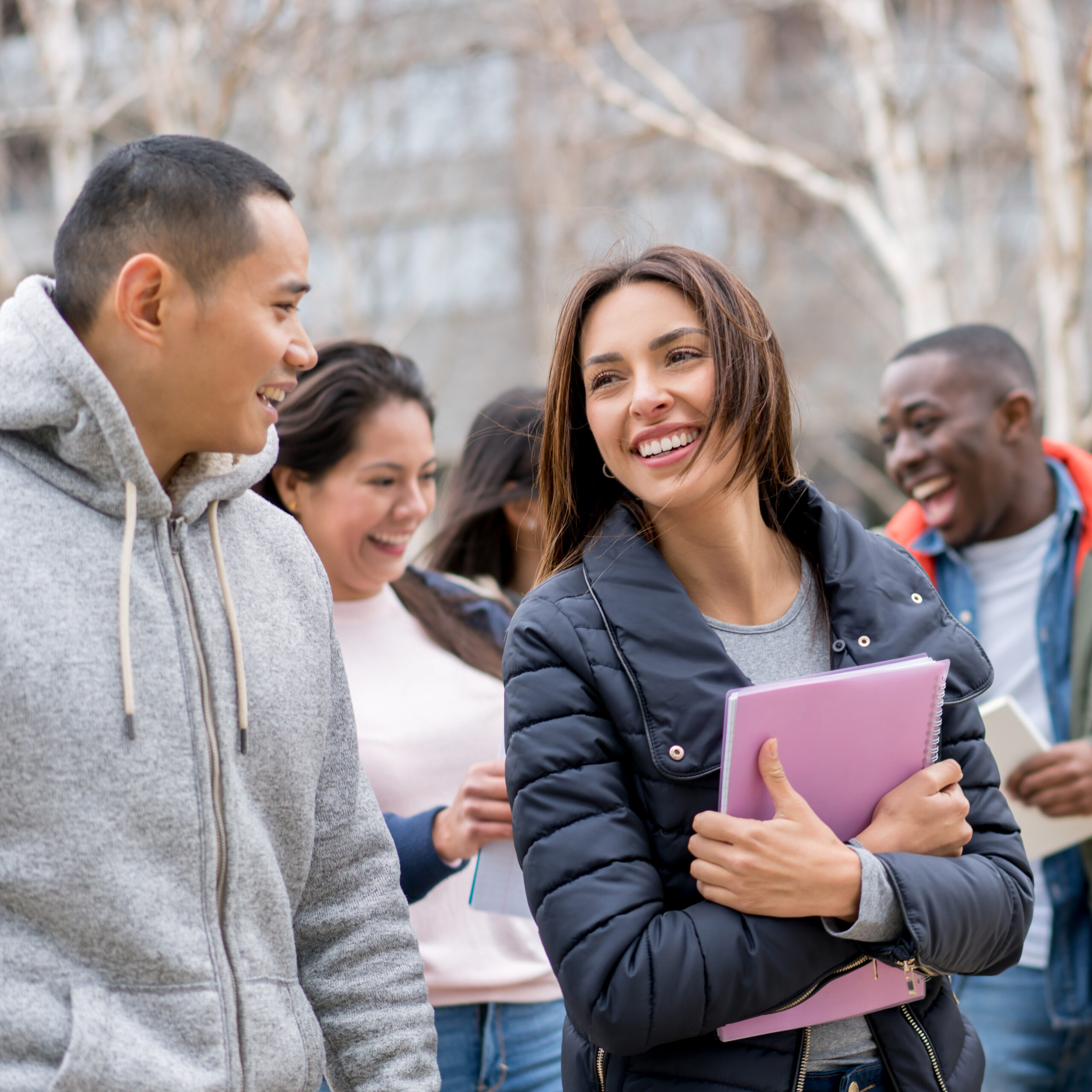 A photograph of four smiling students from different ethnic backgrounds.