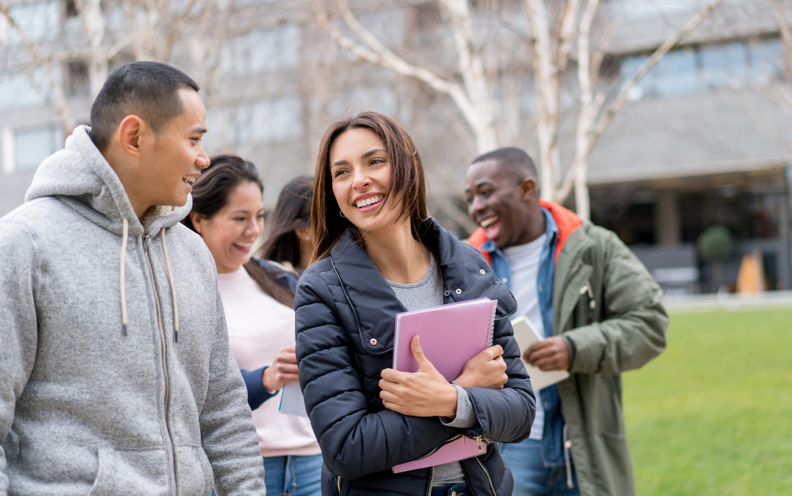 A photograph of four smiling students from different ethnic backgrounds.