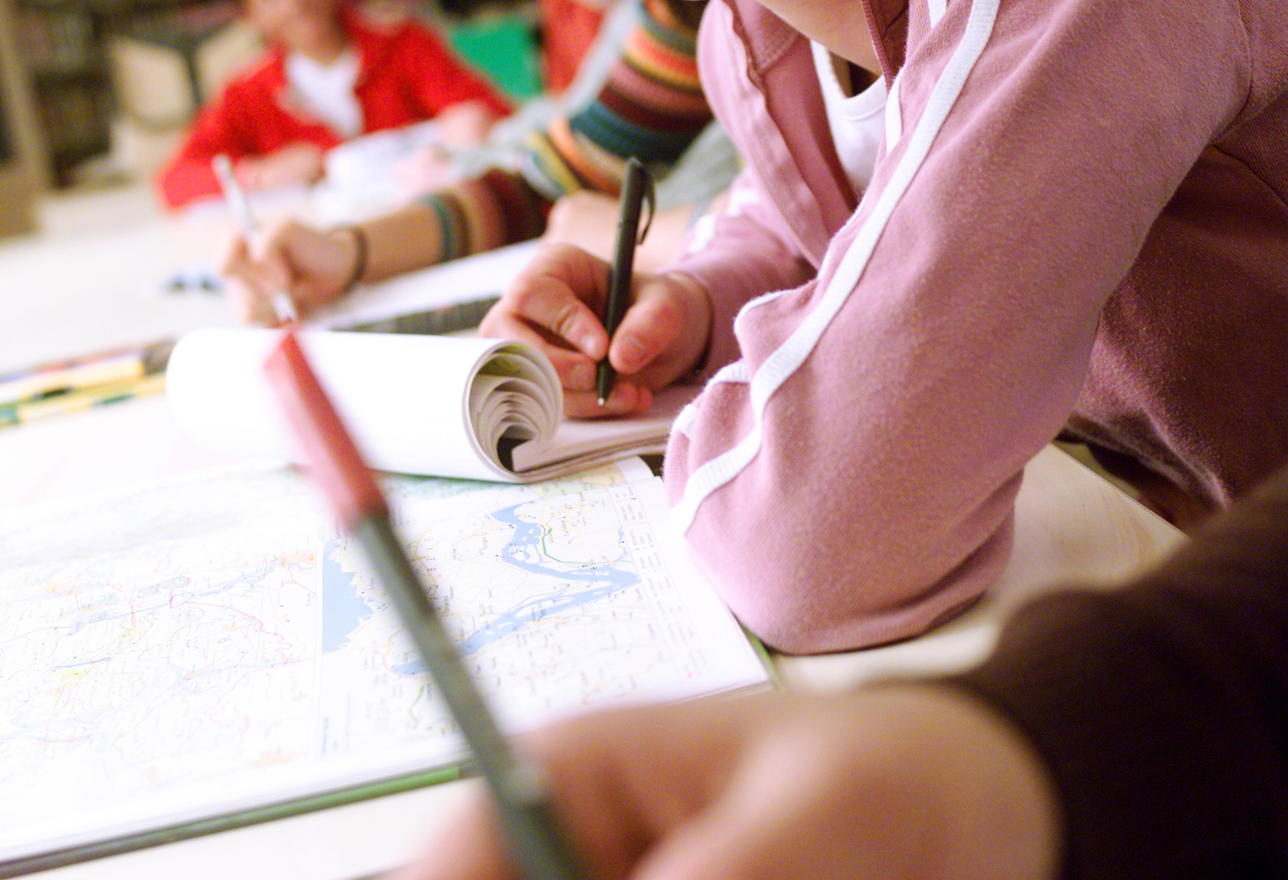 photograph of students resting arm on table holding a pen
