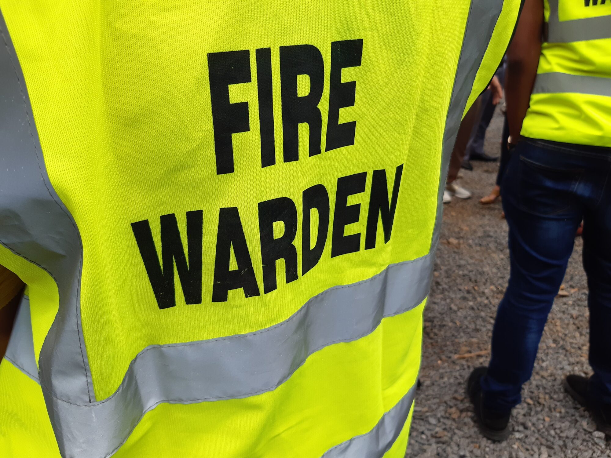 Yellow and grey fire warden tabard with black fire warden writing.