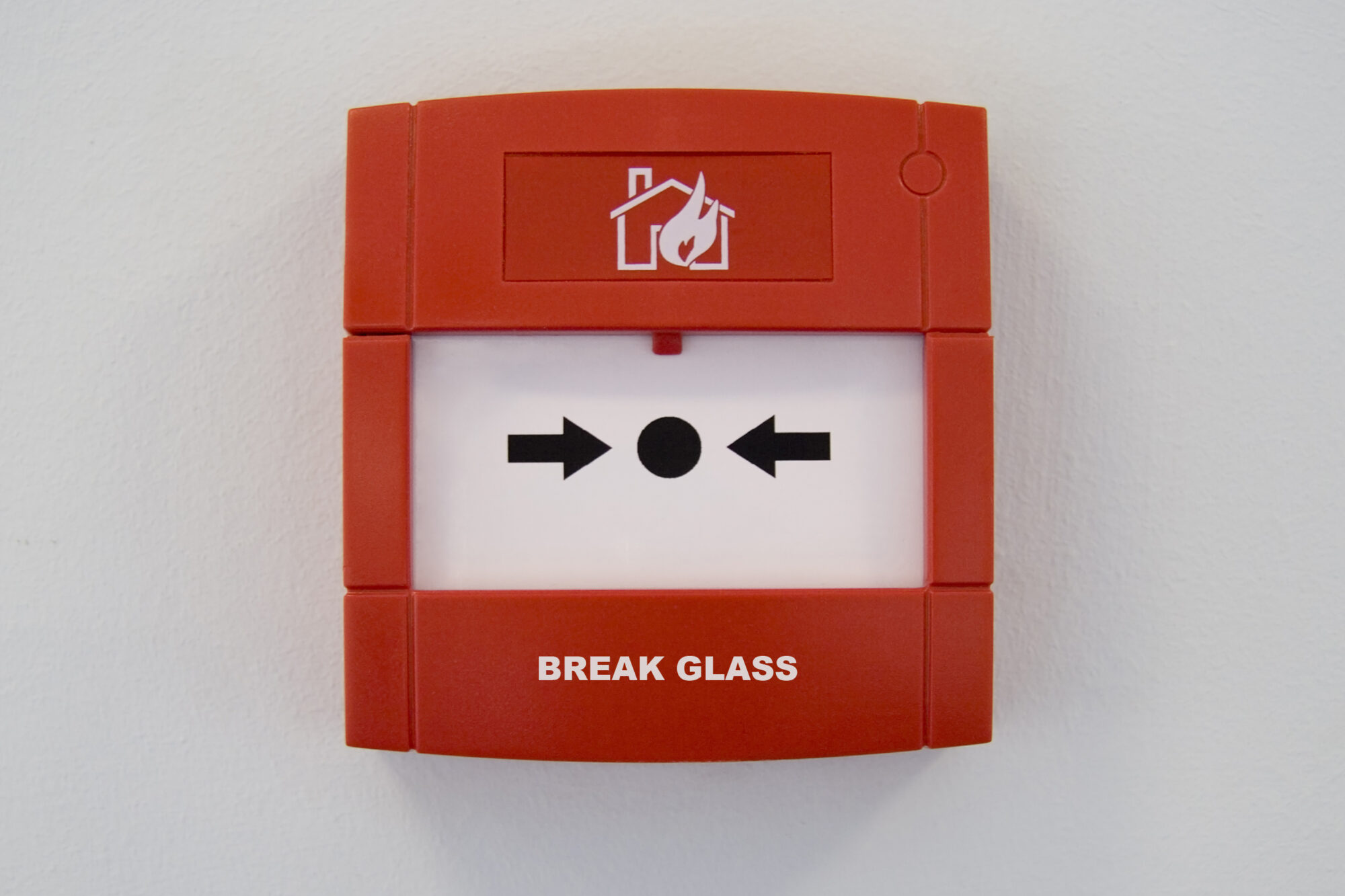 Red fire alarm on the wall with break glass writing in white.
