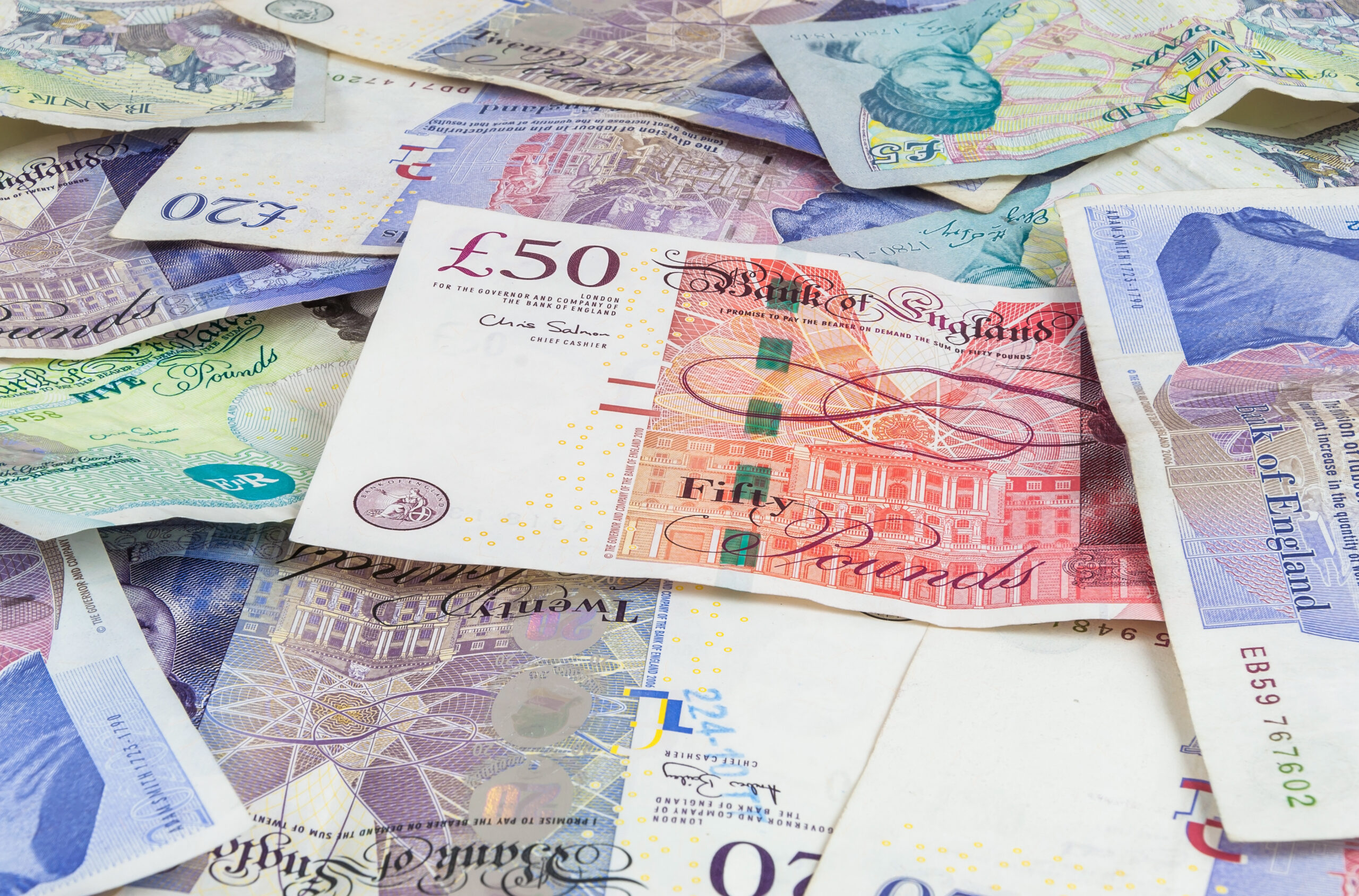 A selection of UK banknotes including fifty, twenty and five pound notes.